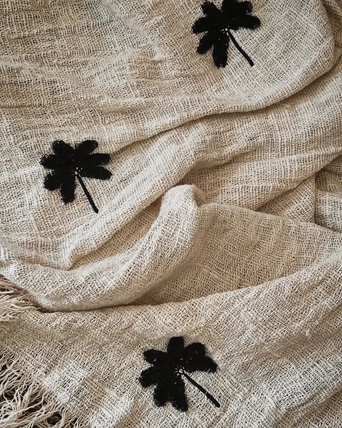 Close up details of black enbroidered palm tree on linen throw blanket