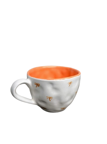 White mug with burnt orange mini palm trees painted on the outside, and a solid orange inside