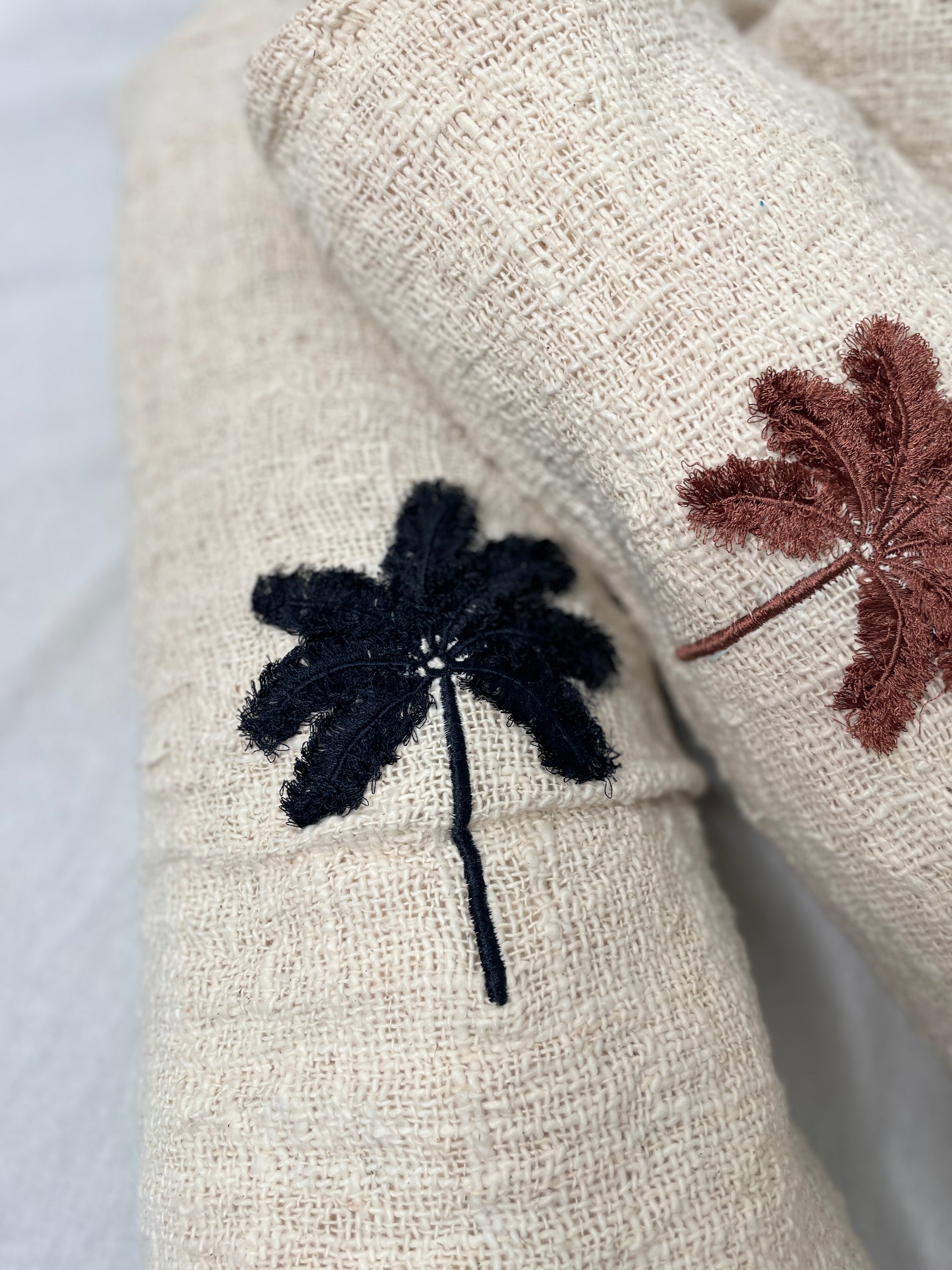 Close up details of natural linen throw blankets with hand embroidered palm trees