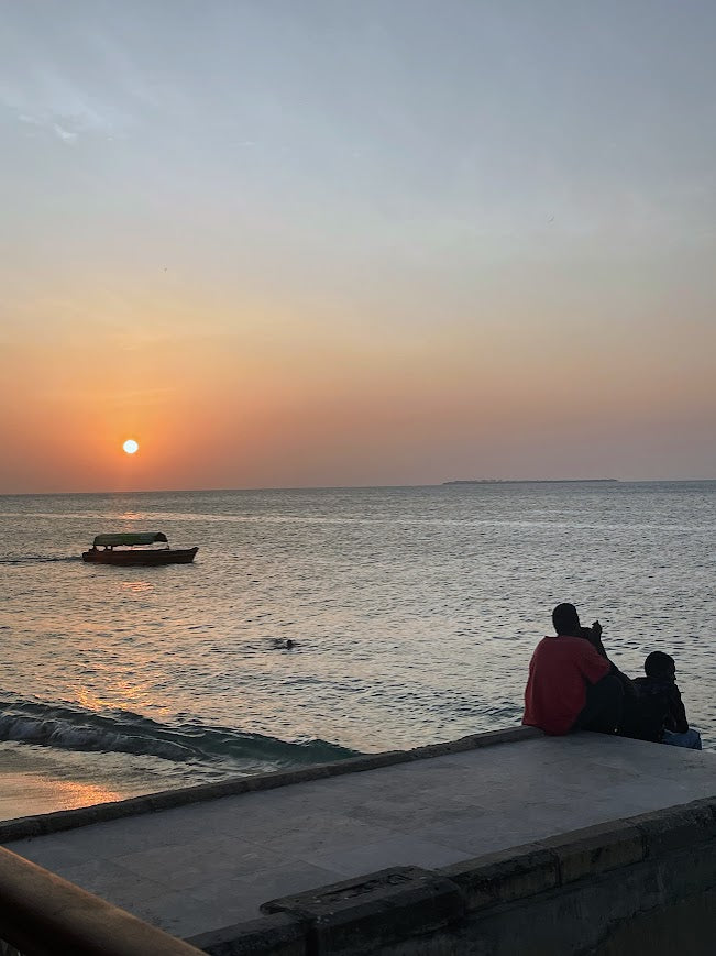 Sunset over ocean with boats and people on the water