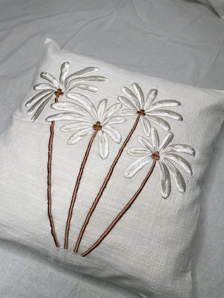 Details of hand sewn white and brown palm trees on a white linen cushion