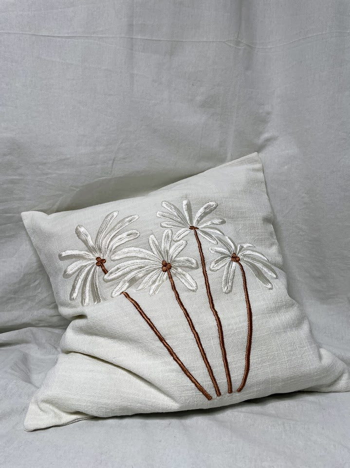 Studio shot of a white linen cushion with white and brown palm trees on the front