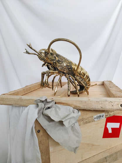 Large brass lobster sitting on top of a packing box