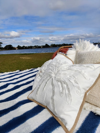 Picnic setting by a river with cushions and throw rugs