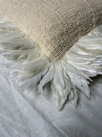 Close up details of white feathers on large natural linen cushion cover