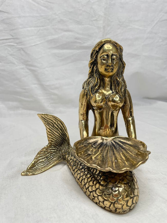 A single brass Mermaid statue sitting with her tail to the side, holding half a clam shell for use as a small bowl or jewellery holder 