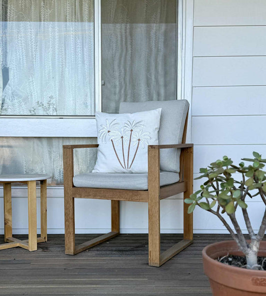 Outdoor furniture with a cushioned chair and table on a wooden deck, featuring a potted plant.