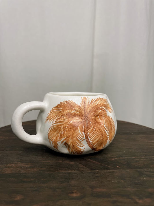 Short and round dimpled mug with single burnt orange palm tree painted on one side  
