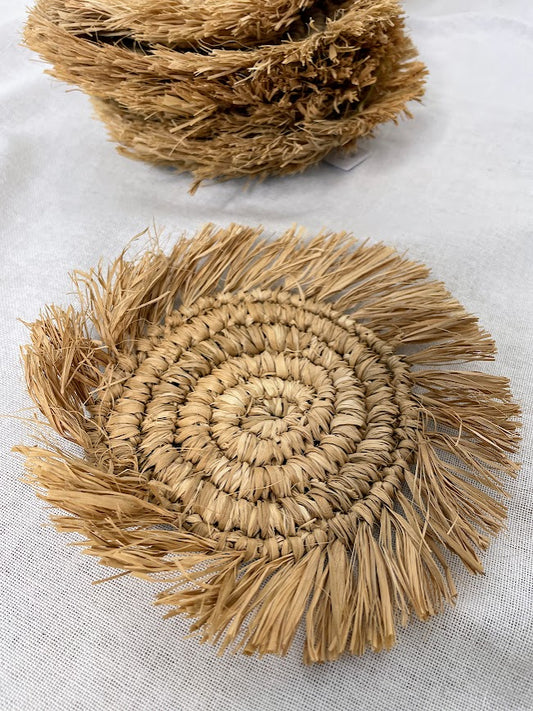 Details of a rafia coaster on a linen backdrop