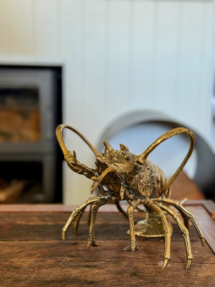 Gold crab sculpture on a wooden surface with a blurred background