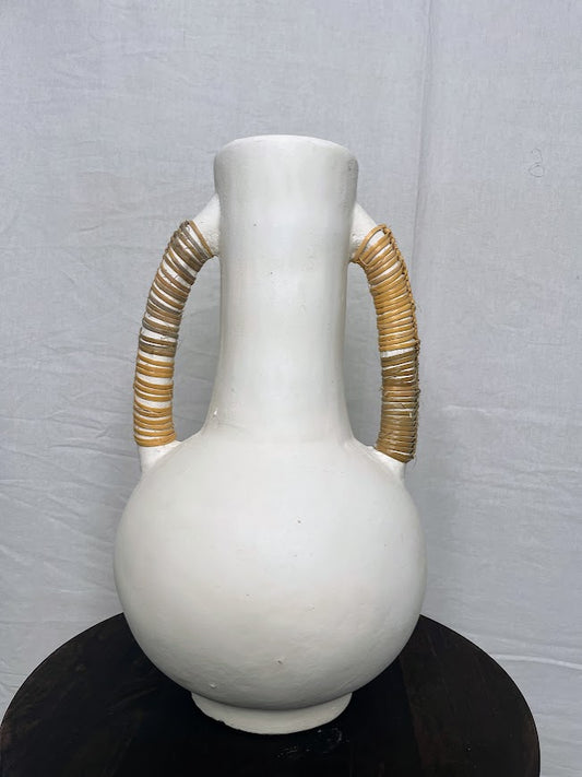 Close up details of a Tall pottery vase in white with two large handles either side, wrapped in rattan
