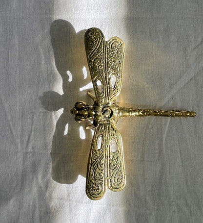 Brass Dragonfly with light coming in through holes in the wings